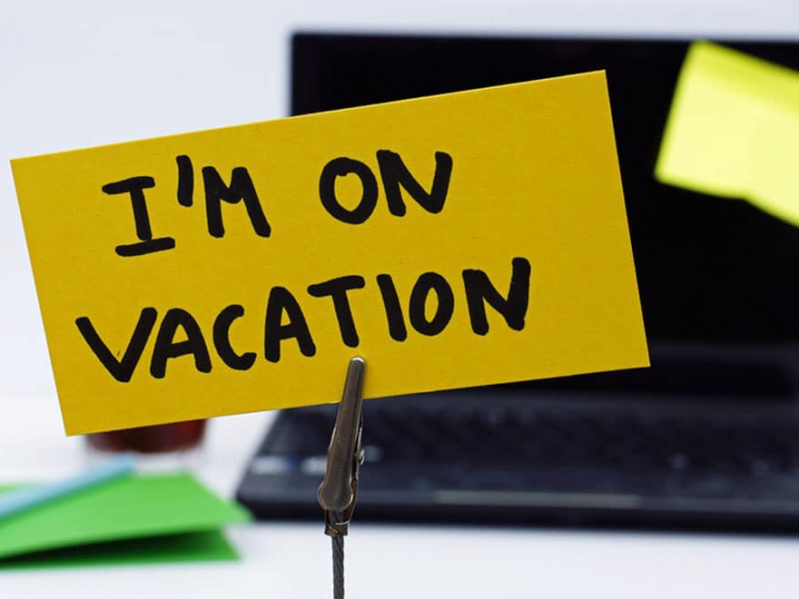 Picture of computer with sign in front of it saying I'm on vacation.