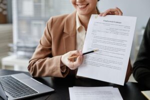 Woman holding an employment contract, pointing to a section on the contract with a pen.