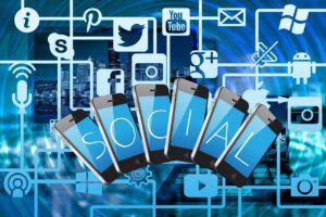 Various, networked social media logos and a set of six cell phones, each with a letter in them spelling SOCIAL in a blue background.